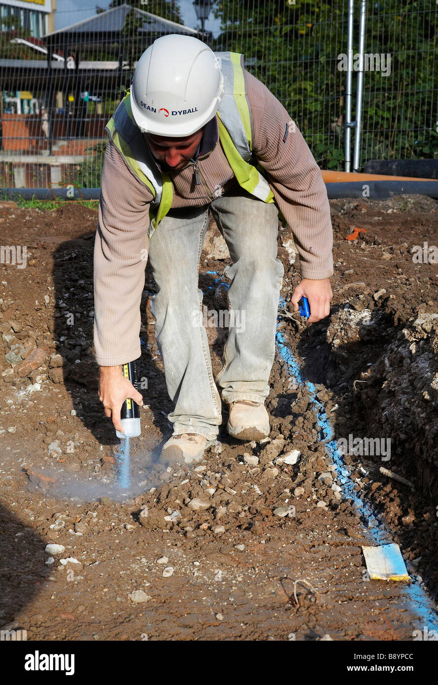 Operaio edile marcatura fuori area per un Jcb a trincea di scavo a Taunton, England, Regno Unito Foto Stock