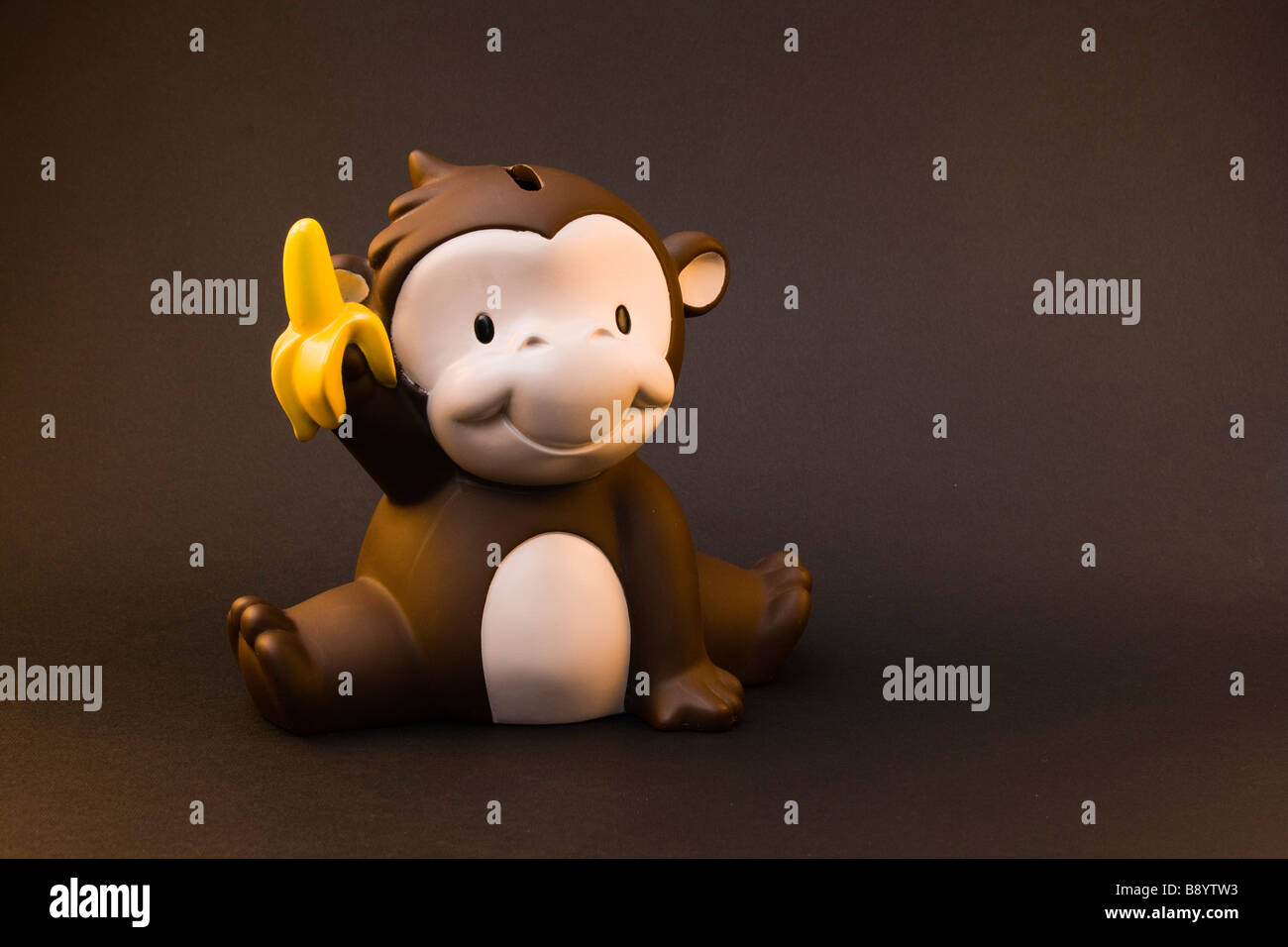 Uno stile cartoon monkey salvadanaio tenere una banana nell'aria. Foto Stock