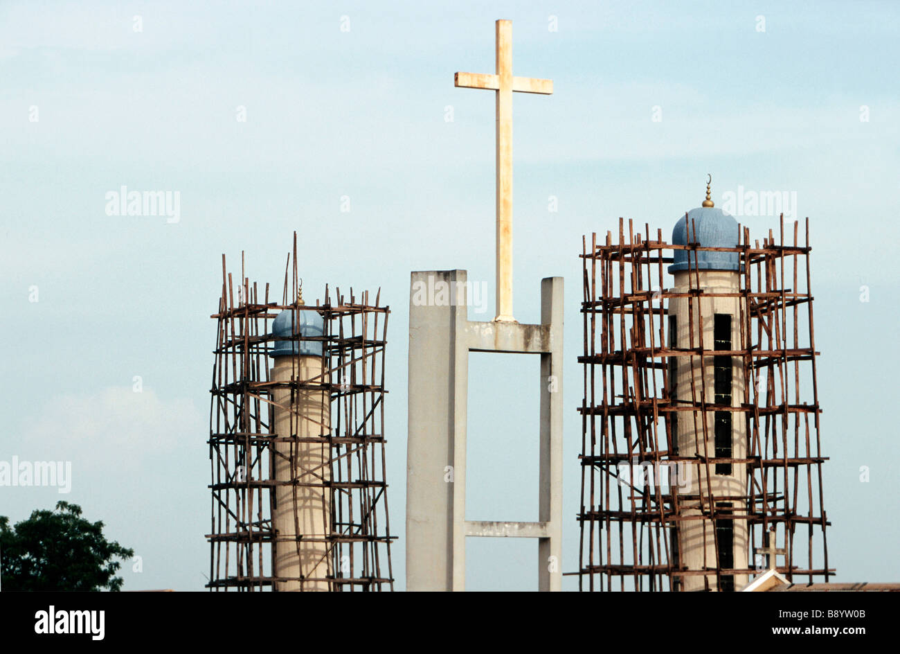 La Nigeria, croce di la romana chiesa carholic tra due minareti della Moschea di Kaduna Foto Stock