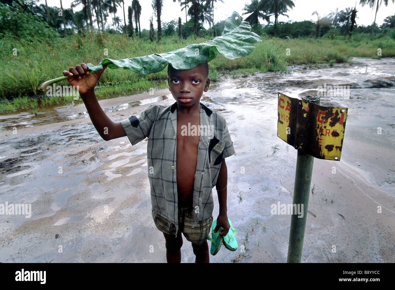 Nigeria: un ragazzo sorge oltre ad un segno di pericolo da olio area contaminata in Ogoniland Foto Stock