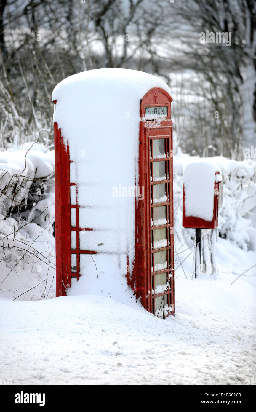 Un tradizionale red britannico casella telefono e casella di posta coperta di neve in North Devon in inverno Foto Stock