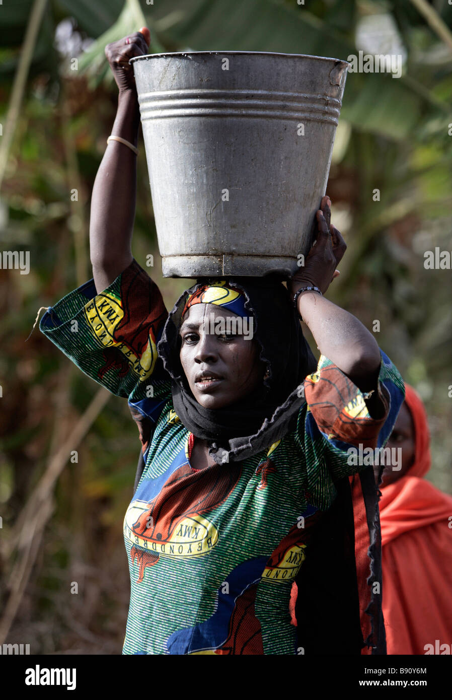 Nigeria: la donna con un secchio di acqua equilibrato sul suo capo Foto Stock