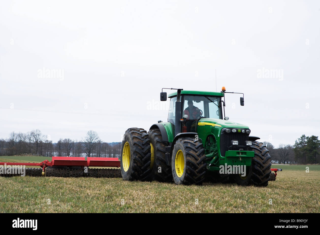 Trattore con rullo in un campo in Svezia. Foto Stock