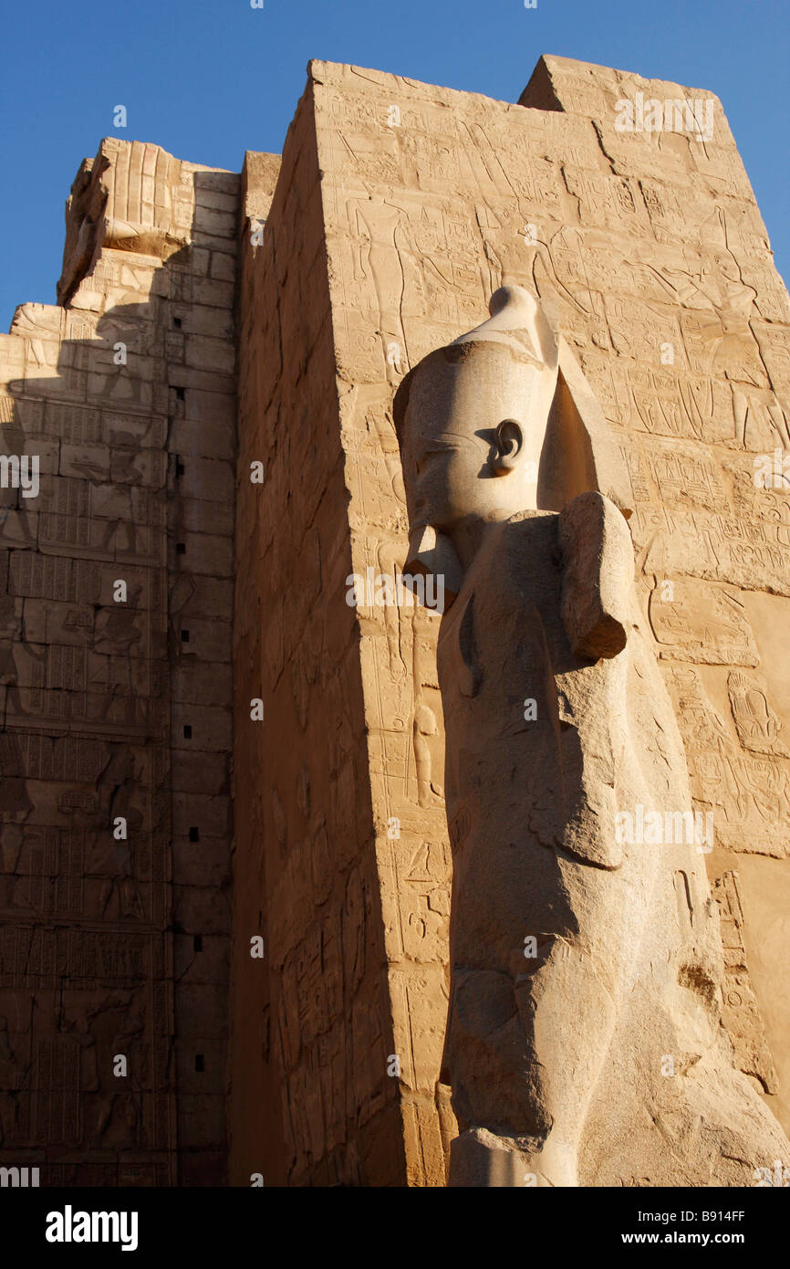 Colossale statua di pietra del faraone Ramses II in ingresso al secondo pilone, Tempio di Karnak Luxor Egitto Foto Stock
