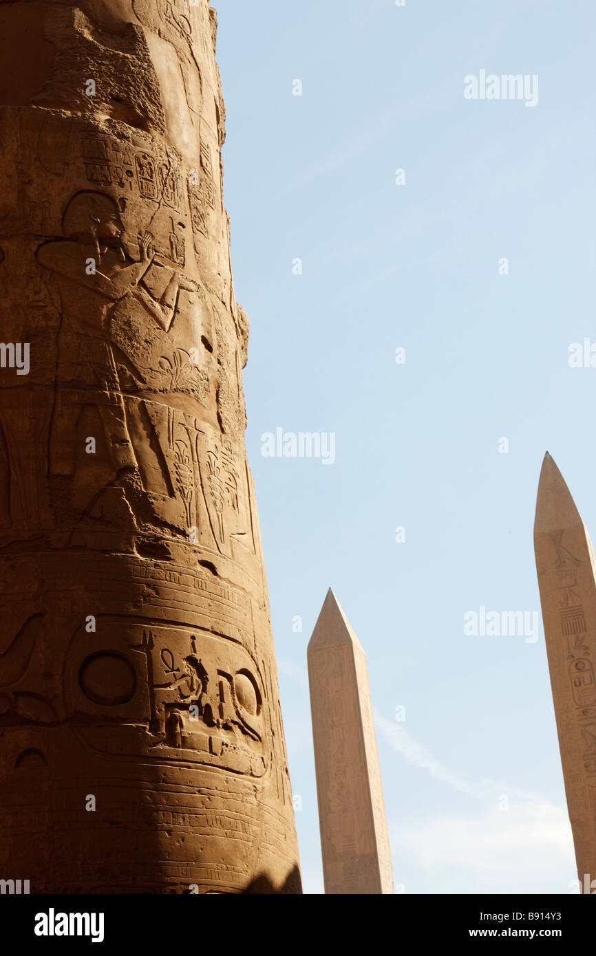 Colonna di pietra scolpita con geroglifici, twin obelischi di Hatshepsut e Thutmosi ho alle spalle, Hypostyle Hall, Karnak Luxor Egitto Foto Stock