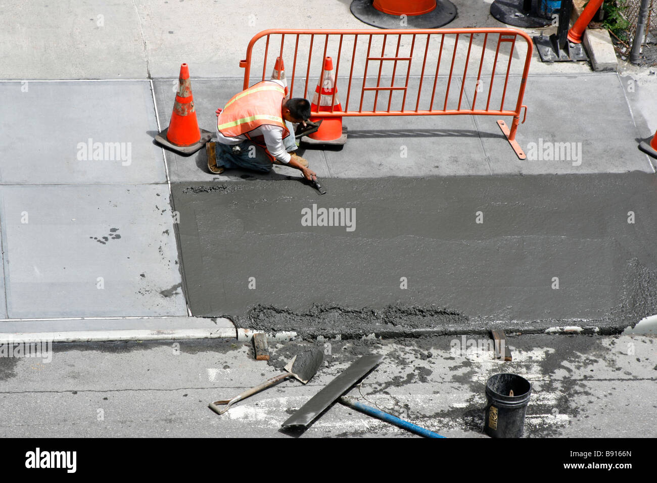 L'uomo una levigatura appena spillata calcestruzzo bagnato il marciapiede. Foto Stock