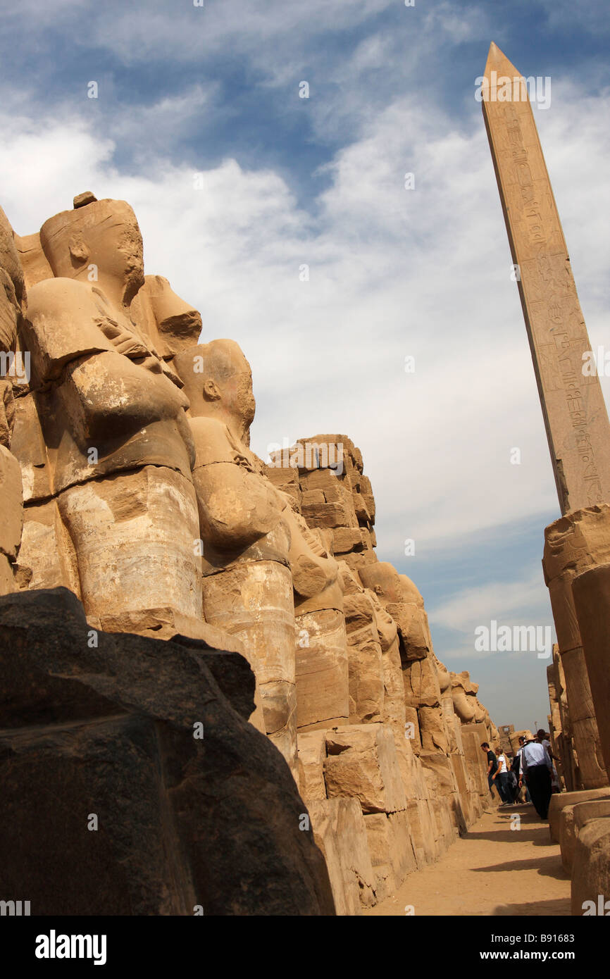 Fila di grandi in pietra scolpita statue di Osiride sotto obelisco della Regina Hatshepsut, Tempio di Karnak Luxor Egitto Foto Stock