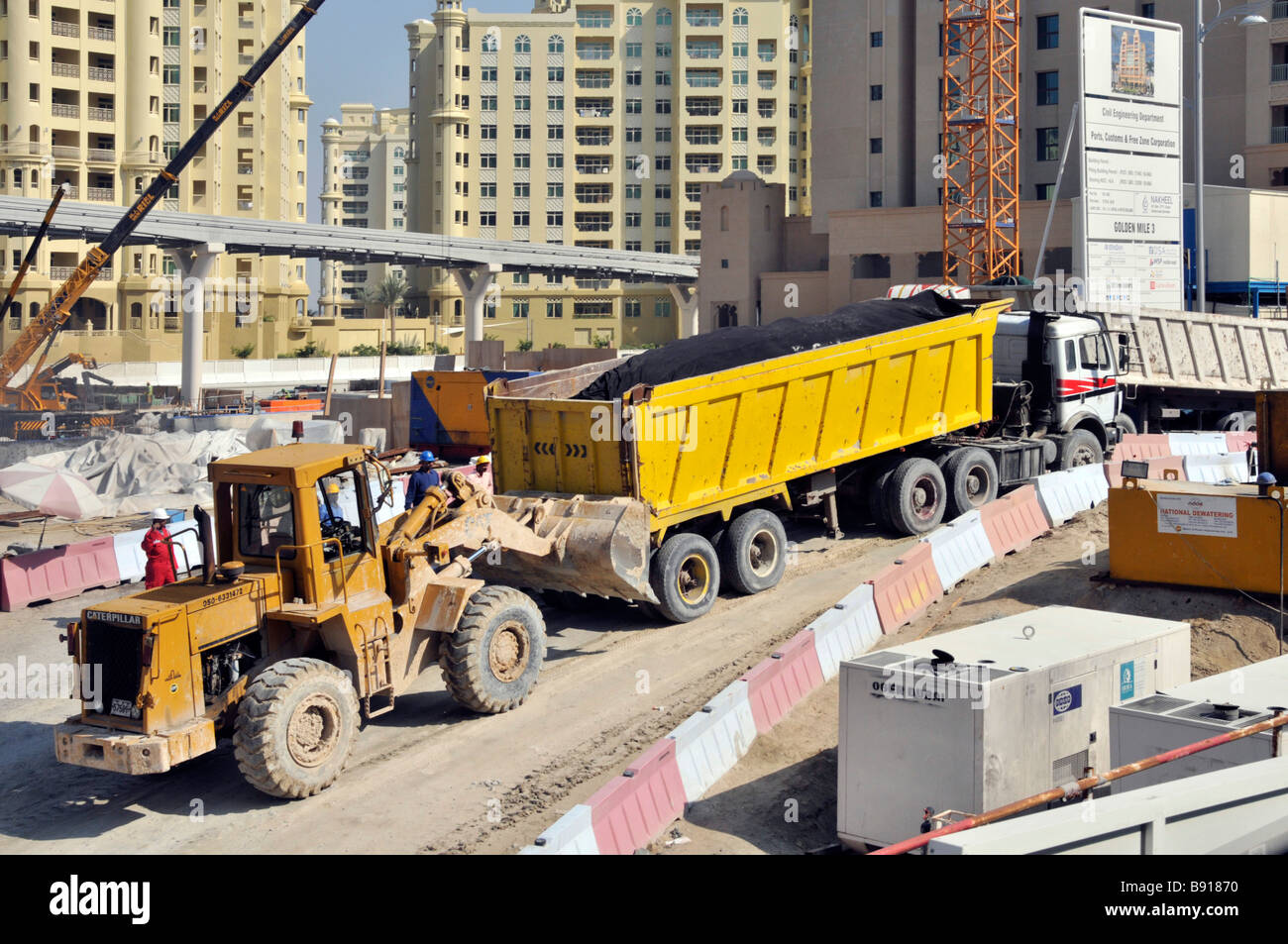 Costruzione di infrastrutture cantiere trattore pala caricatrice dà camion carico un spinta su ripida salita Jumeirah Dubai Emirati Arabi Uniti Foto Stock