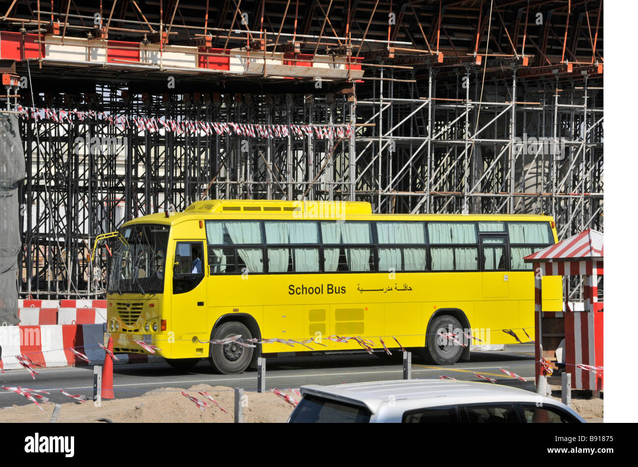 Autobus giallo della scuola di Dubai che passa attraverso impalcature intorno alla costruzione di un ponte Progetto per il nuovo sistema di trasporto aereo metropolitano Emirati Arabi Uniti Foto Stock