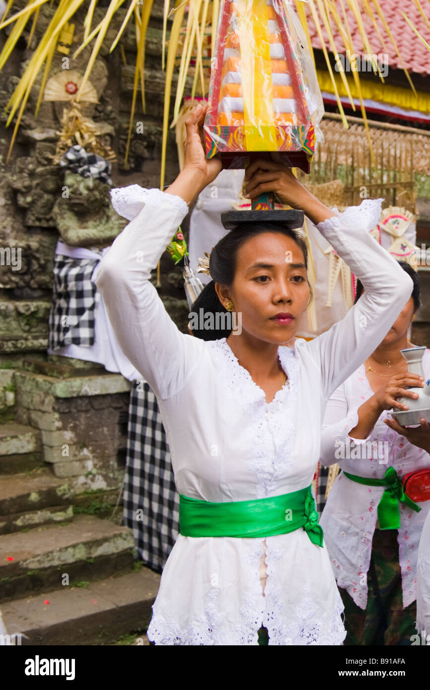 Donna con abbigliamento tradizionale trasporto offerta religiosa in un tempio indù - Bali, Indonesia Foto Stock