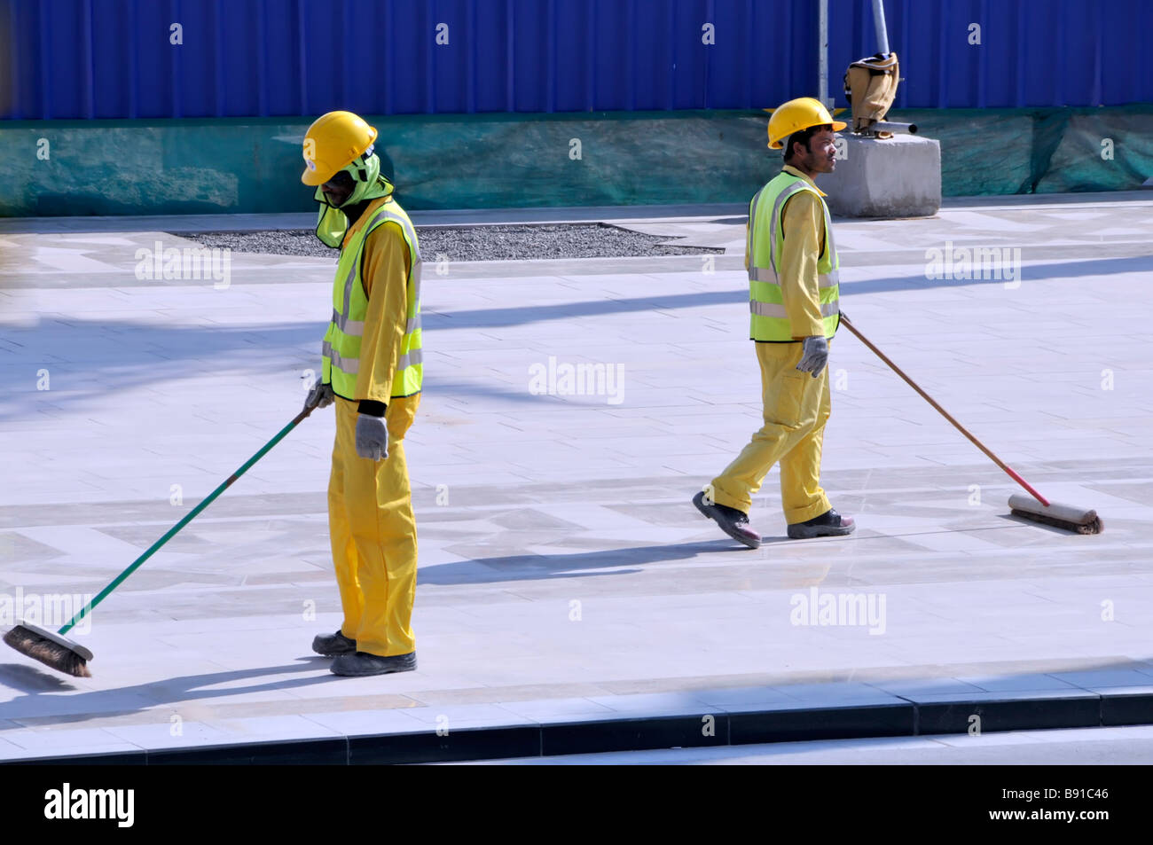 Dubai Mall sviluppo hard Hat high vis costruzione edilizia industria noioso manuale lavoratori del sito spazzare su scopa Emirati Arabi Uniti Emirati Arabi Uniti UAE Foto Stock