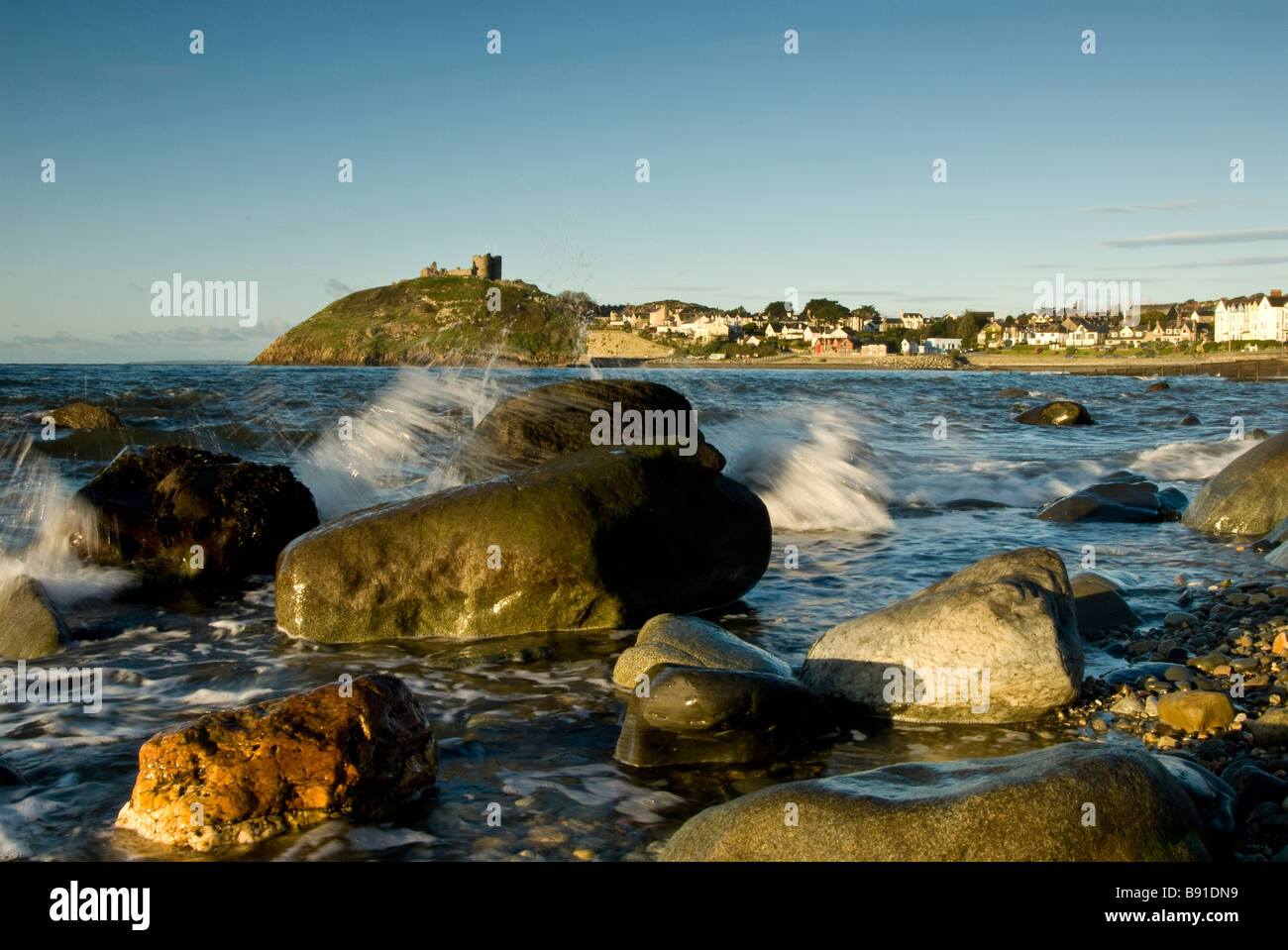 Un litorale roccioso con Criccieth Castle in background, Wales, Regno Unito. Foto Stock