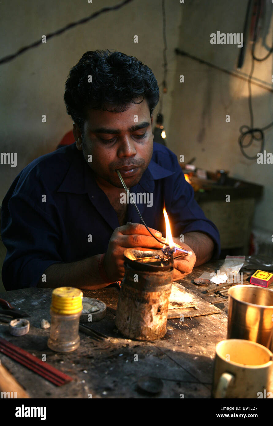 Gli uomini locali creazione di gioielli in una piccola officina per la vendita nel mercato vicino a Mobor in Goa, India Foto Stock