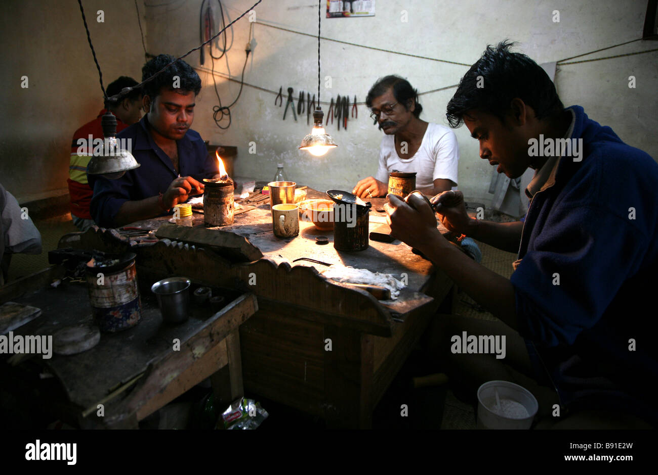 Gli uomini locali creazione di gioielli in una piccola officina per la vendita nel mercato vicino a Mobor in Goa, India Foto Stock