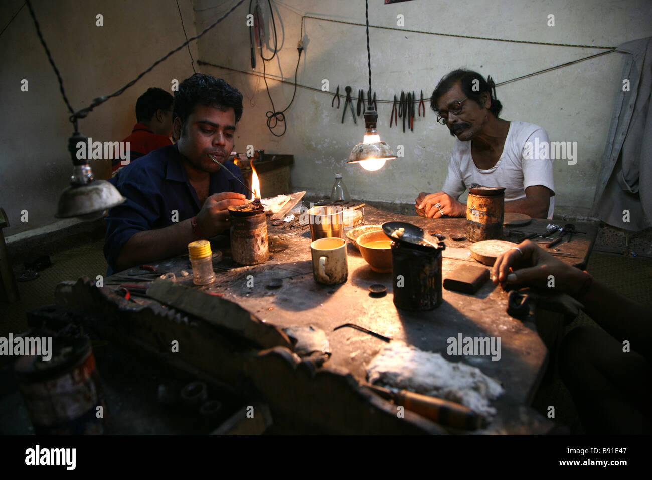 Gli uomini locali creazione di gioielli in una piccola officina per la vendita nel mercato vicino a Mobor in Goa, India Foto Stock