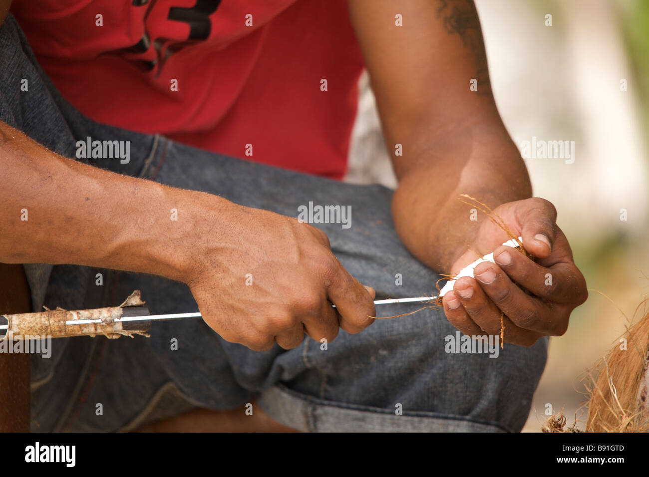 Giovane uomo Bajan realizzazione artigianale di bird feeder dalla buccia di cocco a gru "spiaggia", Barbados, 'West Indies' Foto Stock