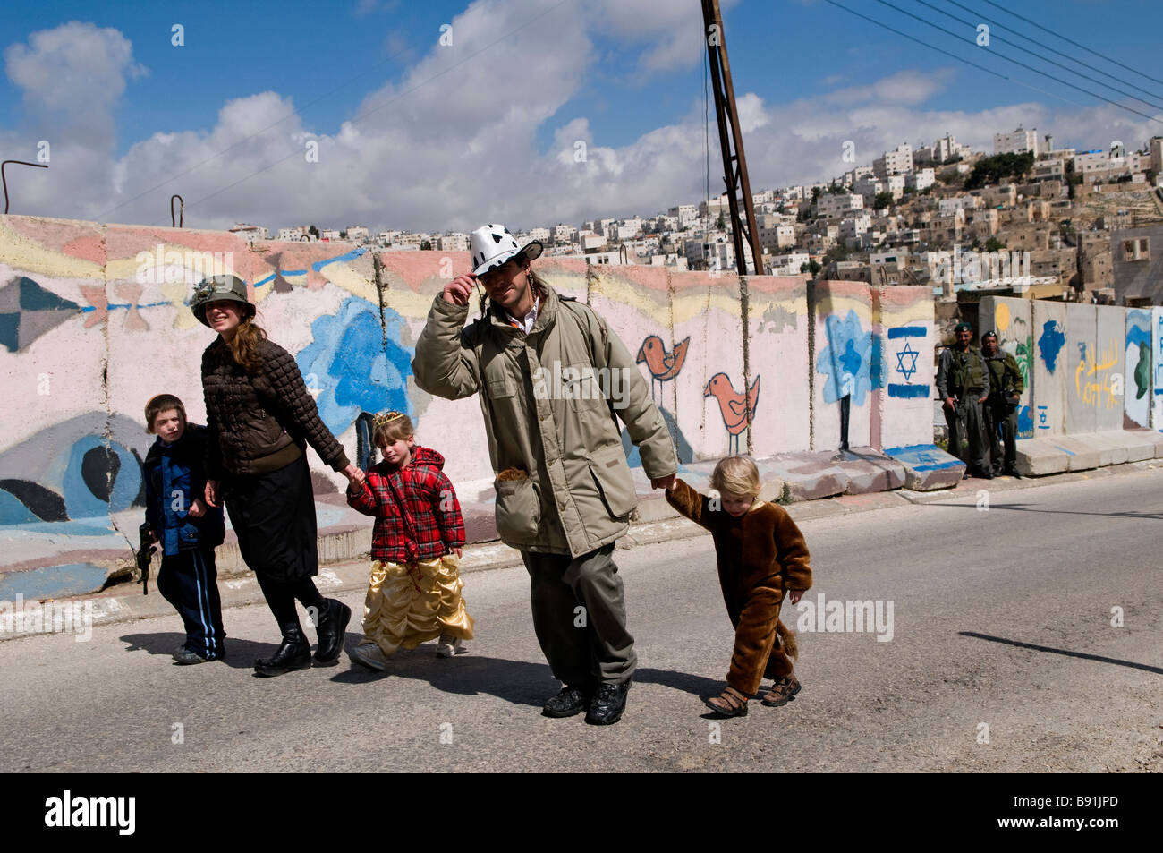 Coloni ebrei a piedi lungo le lastre di cemento separando quartiere palestinese di Bab a-Zawiya e H-2 controllo israeliano area in Hebron Cisgiordania Foto Stock