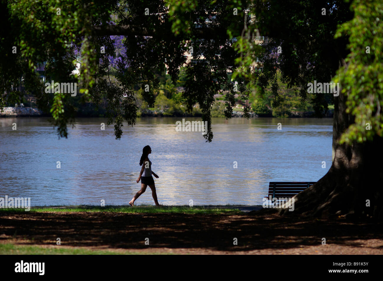 Donna che cammina accanto al fiume Foto Stock