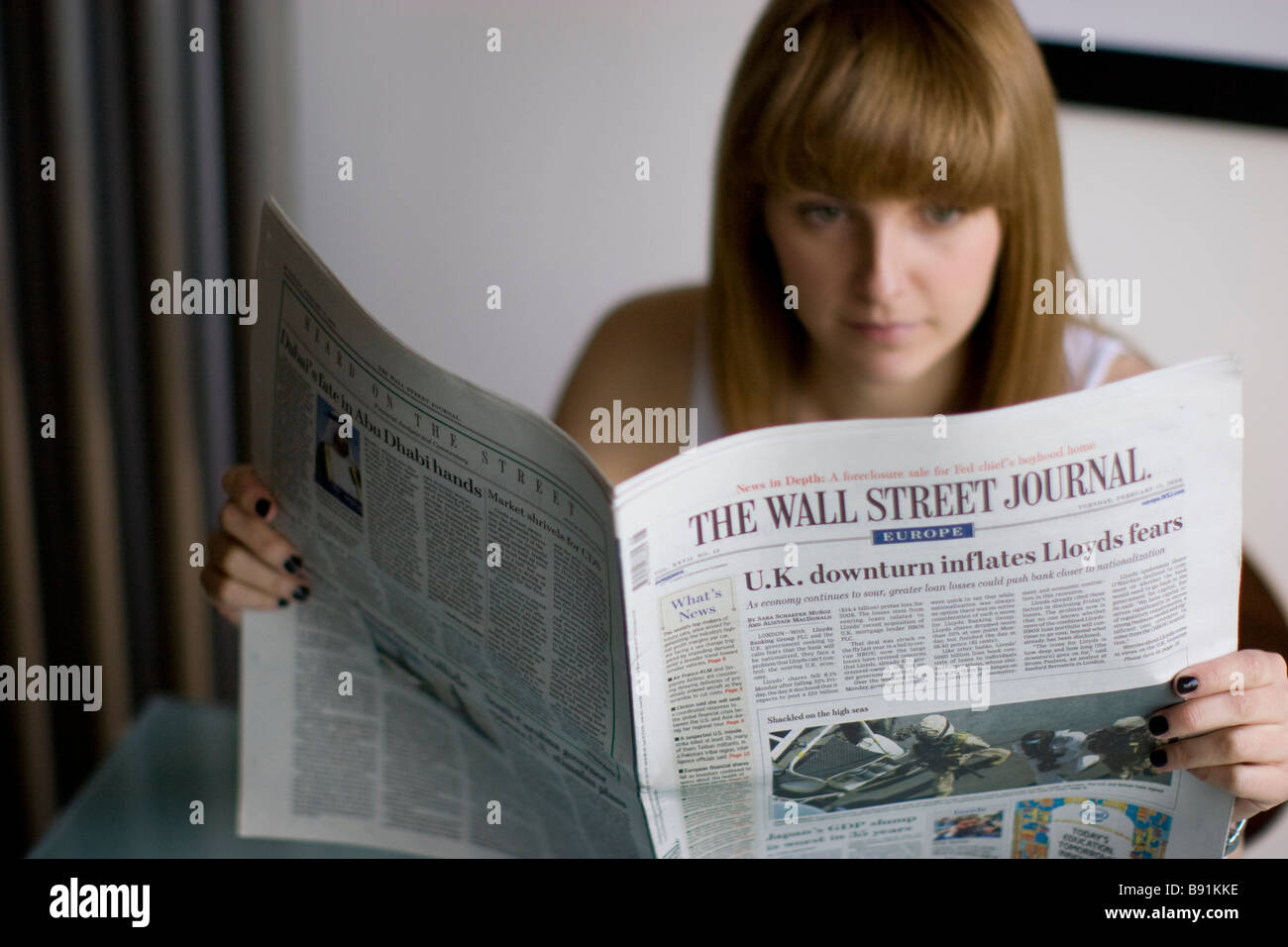 Giovane femmina la lettura del Wall Street Journal usa american quotidiano finanziario Foto Stock