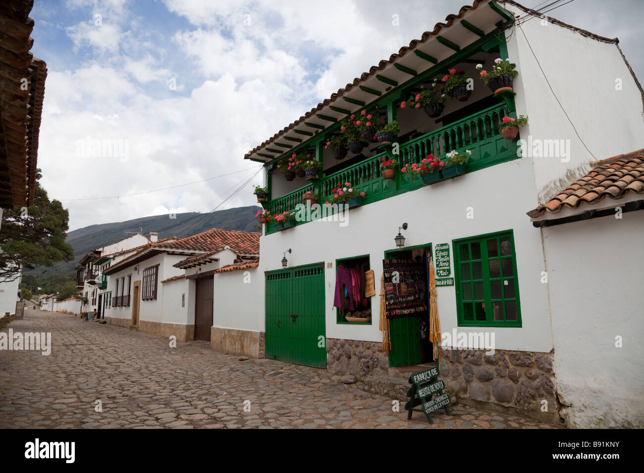 Strada tipica e memorizzare in Villa de Leyva, Colombia, mostrando le strade acciottolate, pareti dipinte di bianco, verde i dettagli. Foto Stock