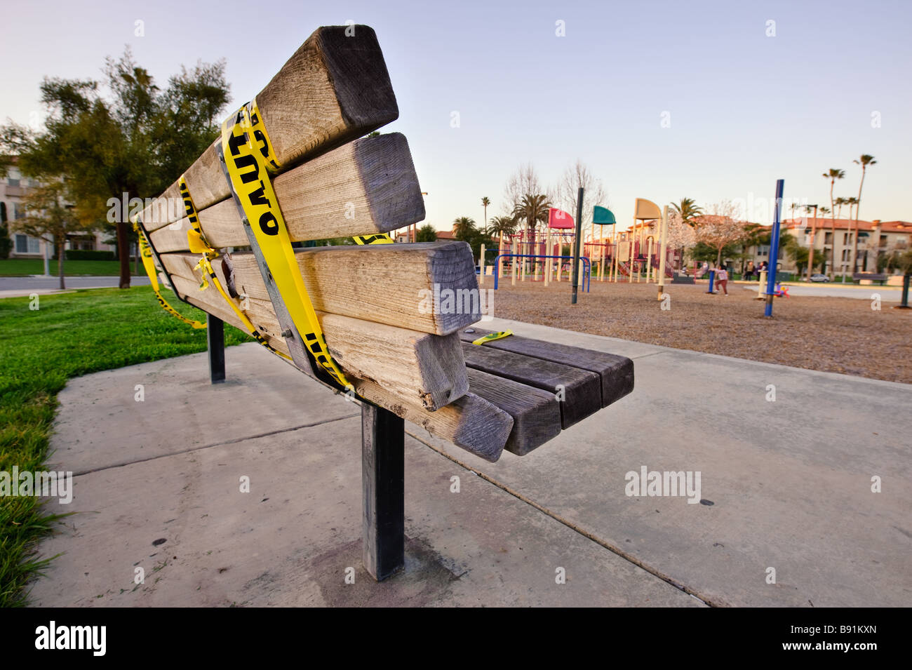Svuotare una panchina nel parco con un catione il nastro avvolto intorno ad esso con un' per bambini Parco giochi in background. Foto Stock