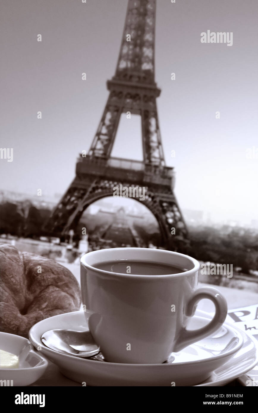 Francese colazione a base di caffè e croissant sul tavolo con libro guida e Torre Eiffel dietro Parigi Francia B+W Ian Shaw Foto Stock