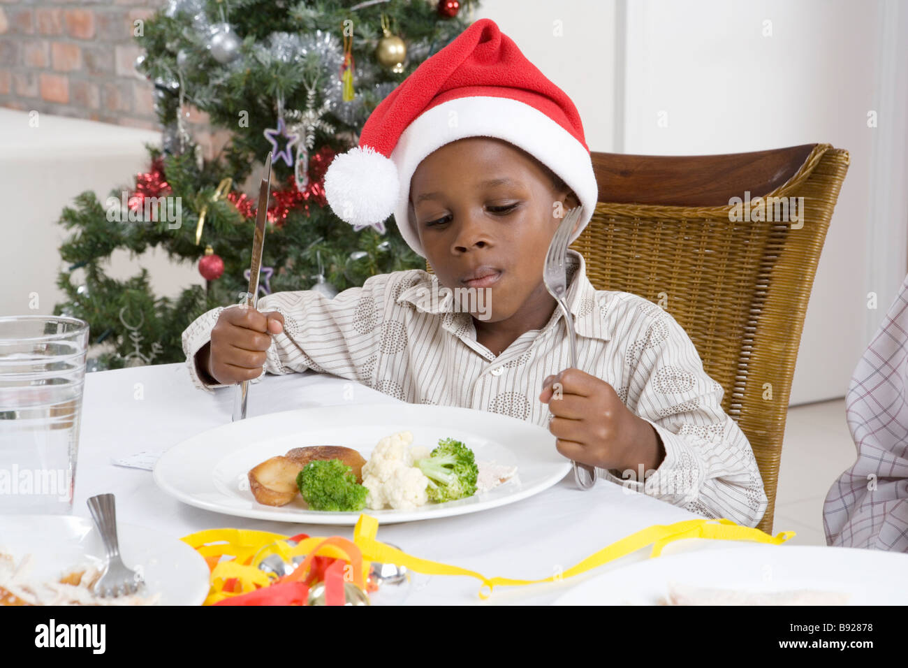 Ragazzo con un cappello di Natale su occhiatura fuori le sue verdure a pranzo di Natale Foto Stock
