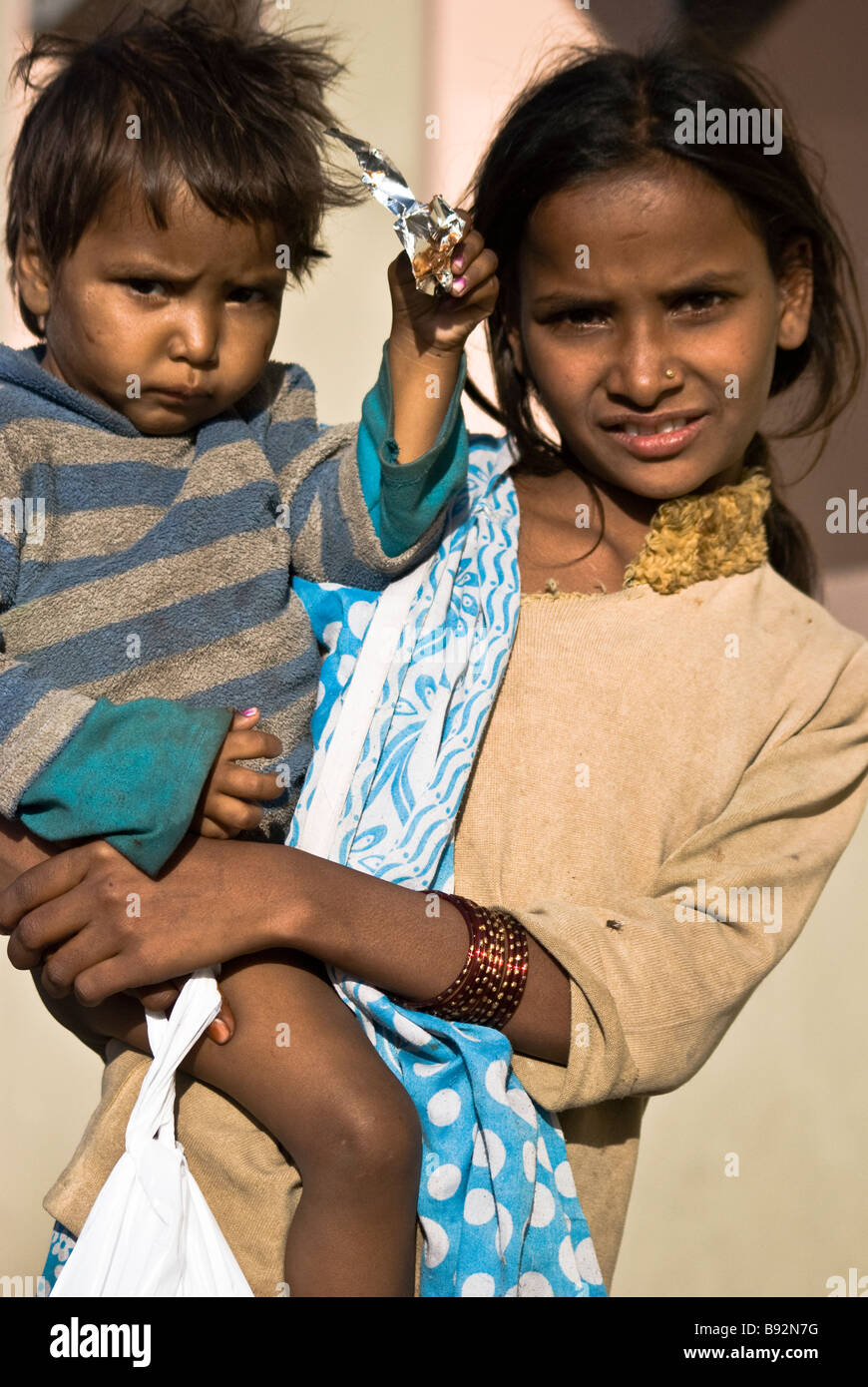 L'intoccabile, senzatetto bambino in India tenendo un bambino utilizzato per colpa di denaro da turisti. Una comune truffa a Jaipur. Foto Stock