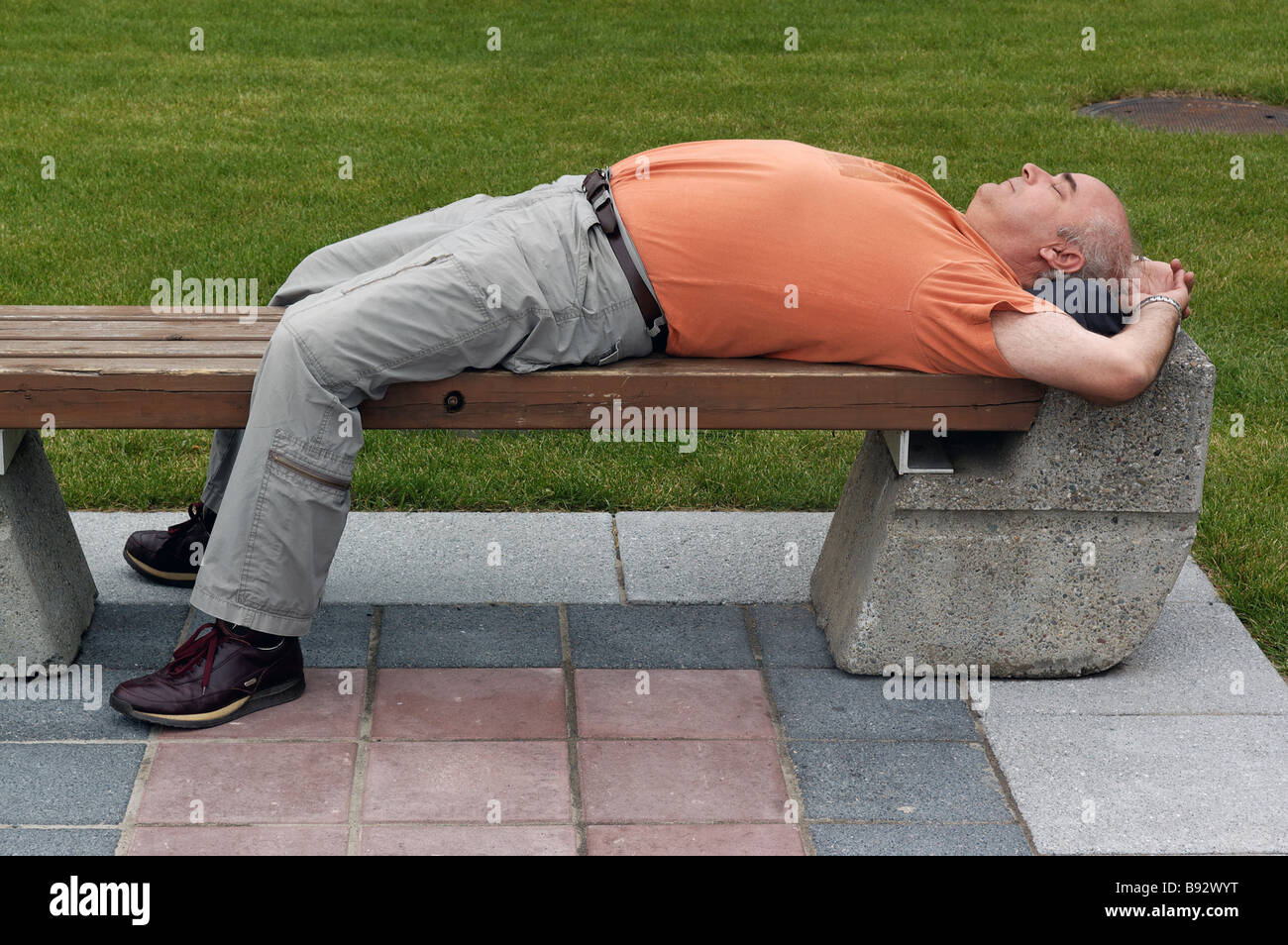 Un uomo addormentato veloce su una sede pubblica Foto Stock