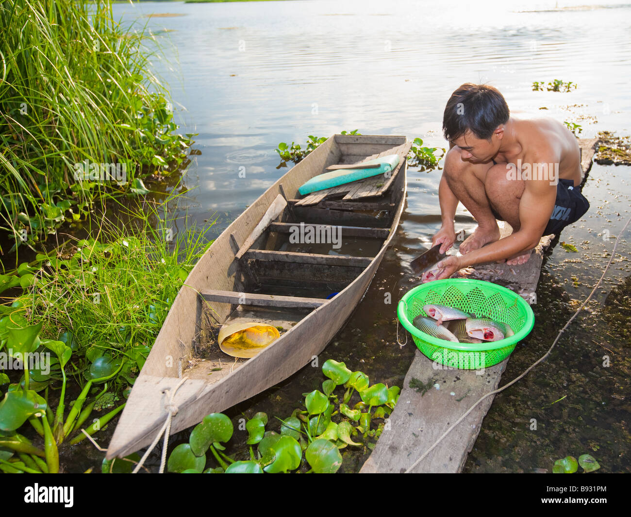 Uomo vietnamita tagliare il pesce nei pressi della barca Foto Stock