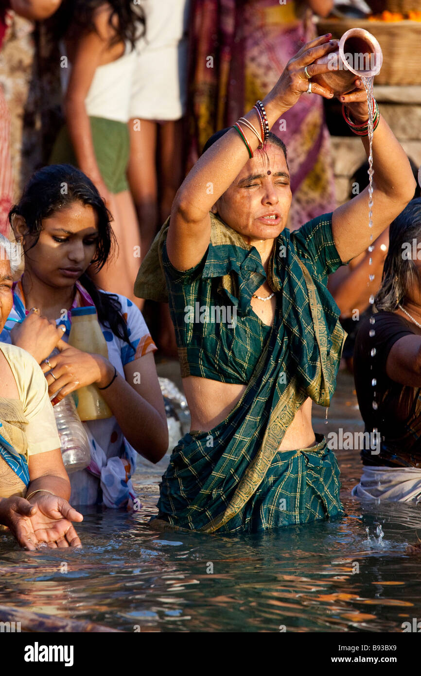 Donna indù rendendo offrendo nel fiume Gange a Varanasi India Foto Stock
