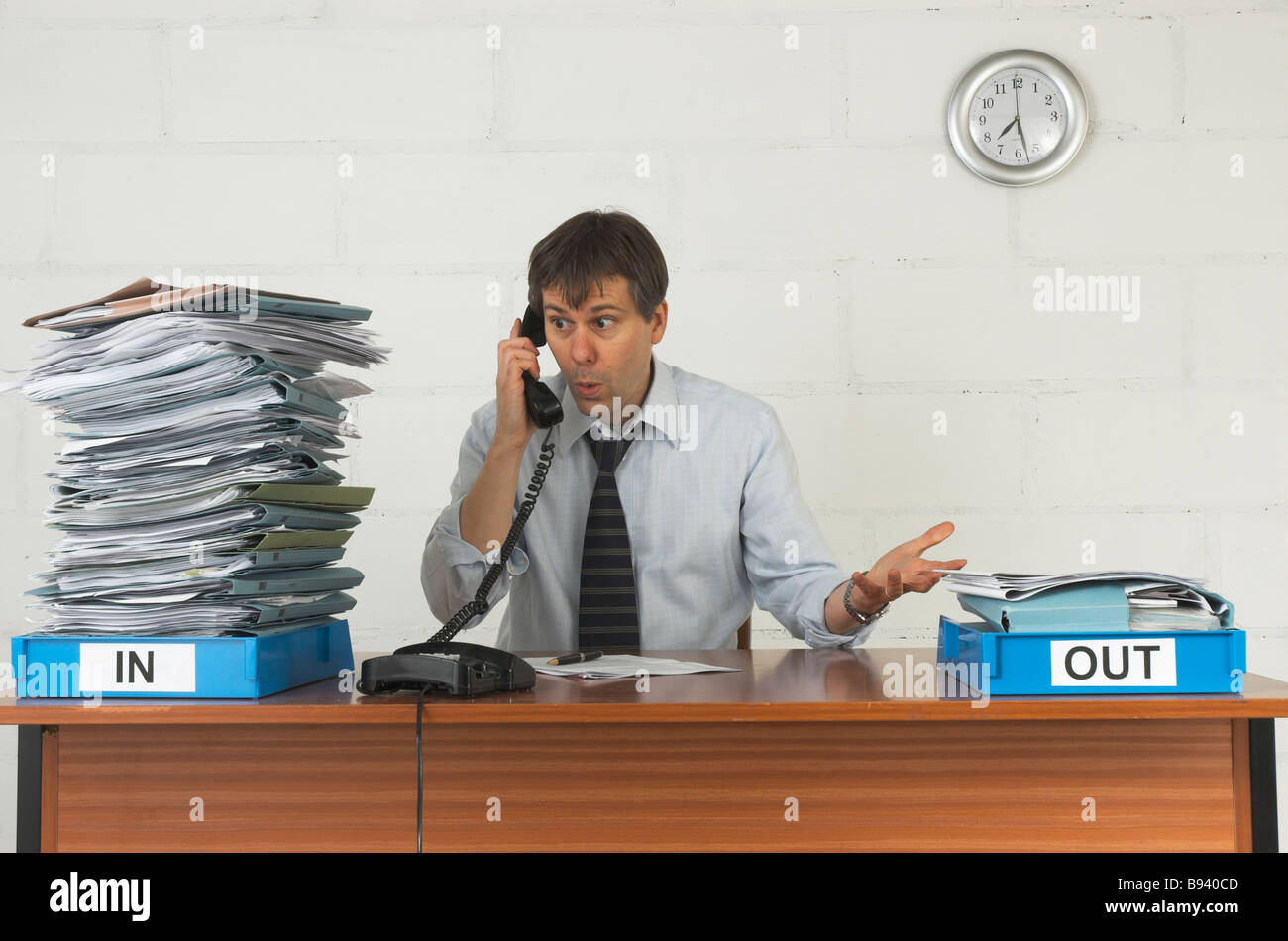 Sottolineato lavoratore di ufficio lavorare fino a tarda sera con un gran mucchio di lavorare nella sua nel vassoio. Foto Stock