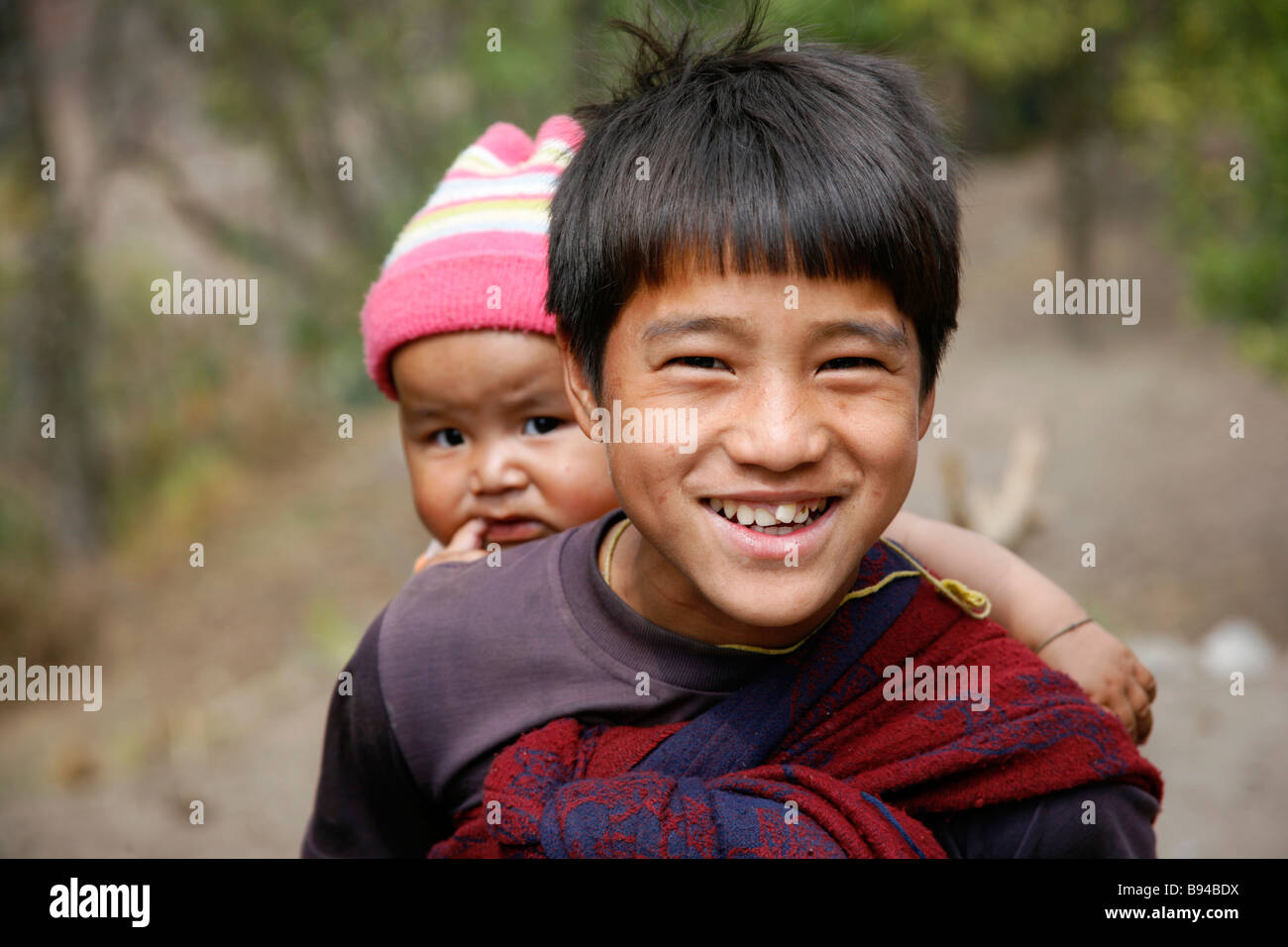 Annapurna Nepal 19 marzo 2008 Giovane ragazzo portando la sua sorella del bambino durante il tentativo di tease del trekking per alimenti Foto Stock