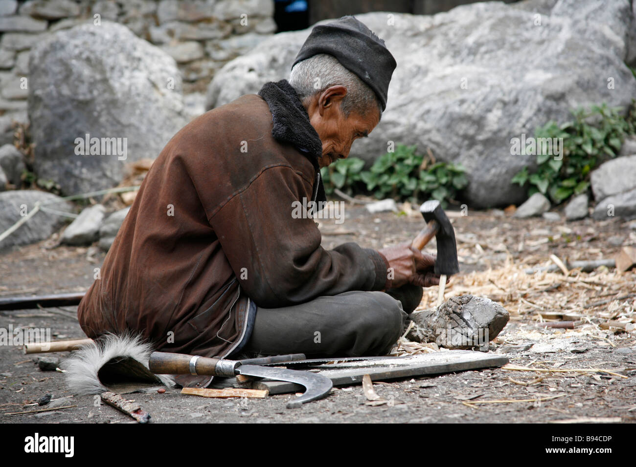 Annapurna Nepal 20 marzo 2008 il vecchio uomo che ripara i suoi attrezzi agricoli in villaggio Foto Stock
