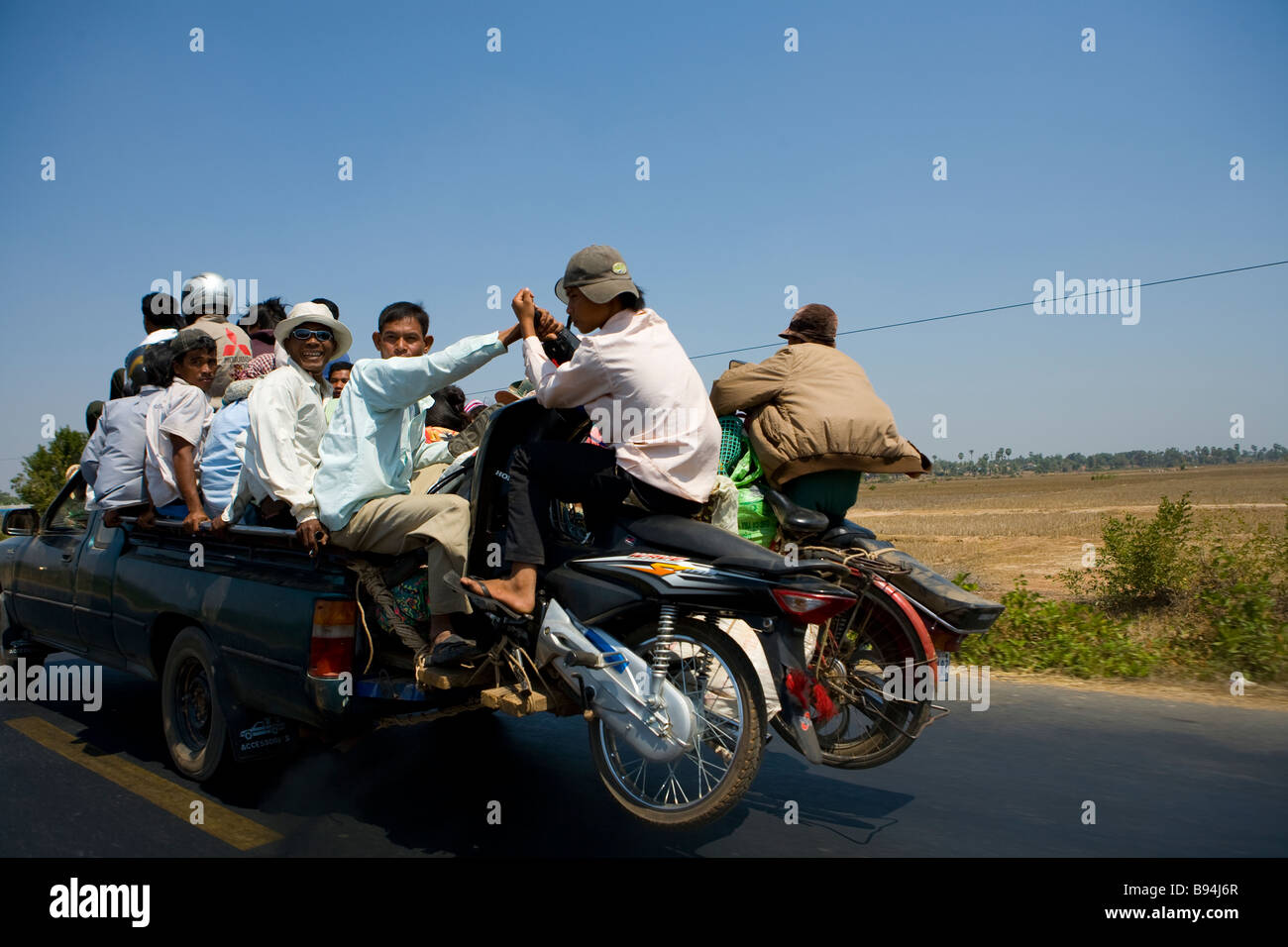 Gli uomini e le motociclette pack su un carrello a cavallo lungo la strada che da Phnom Penh di Kompong Chhang Foto Stock