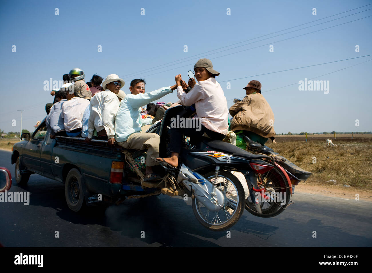 Gli uomini e le motociclette pack su un carrello a cavallo lungo la strada che da Phnom Penh di Kompong Chhang Foto Stock