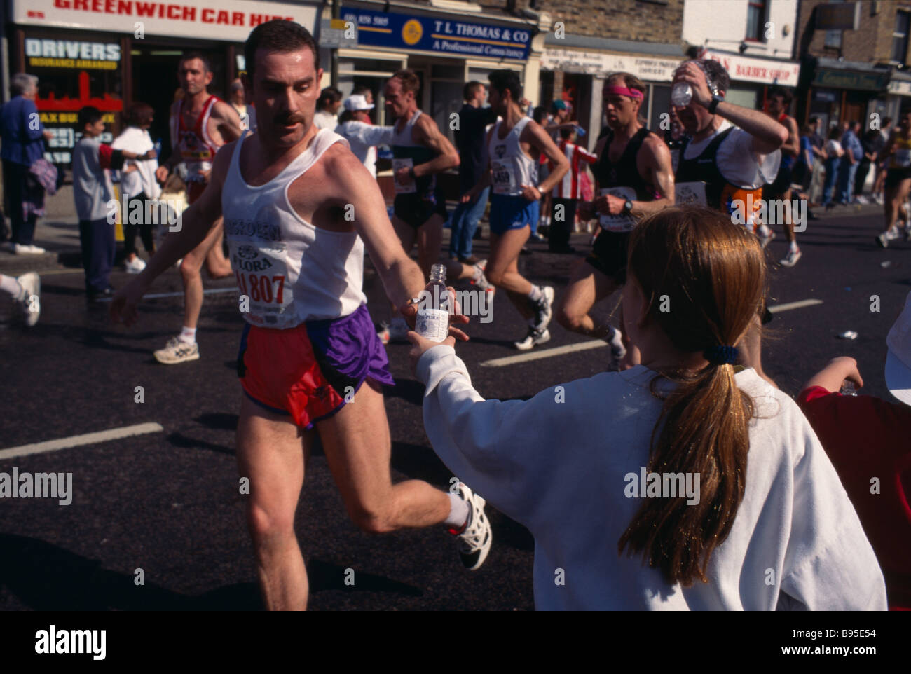 SPORT atletica maratona concorrente nella maratona di Londra raggiungendo per acqua offerto dal bordo della strada a Greenwich sei miglia punto. Foto Stock