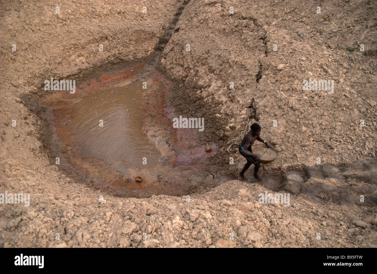 MALI West African uomo che porta una ciotola di acqua fino a gradini ripidi da waterhole per irrigare il suo cipolle in periodo di siccità. Foto Stock
