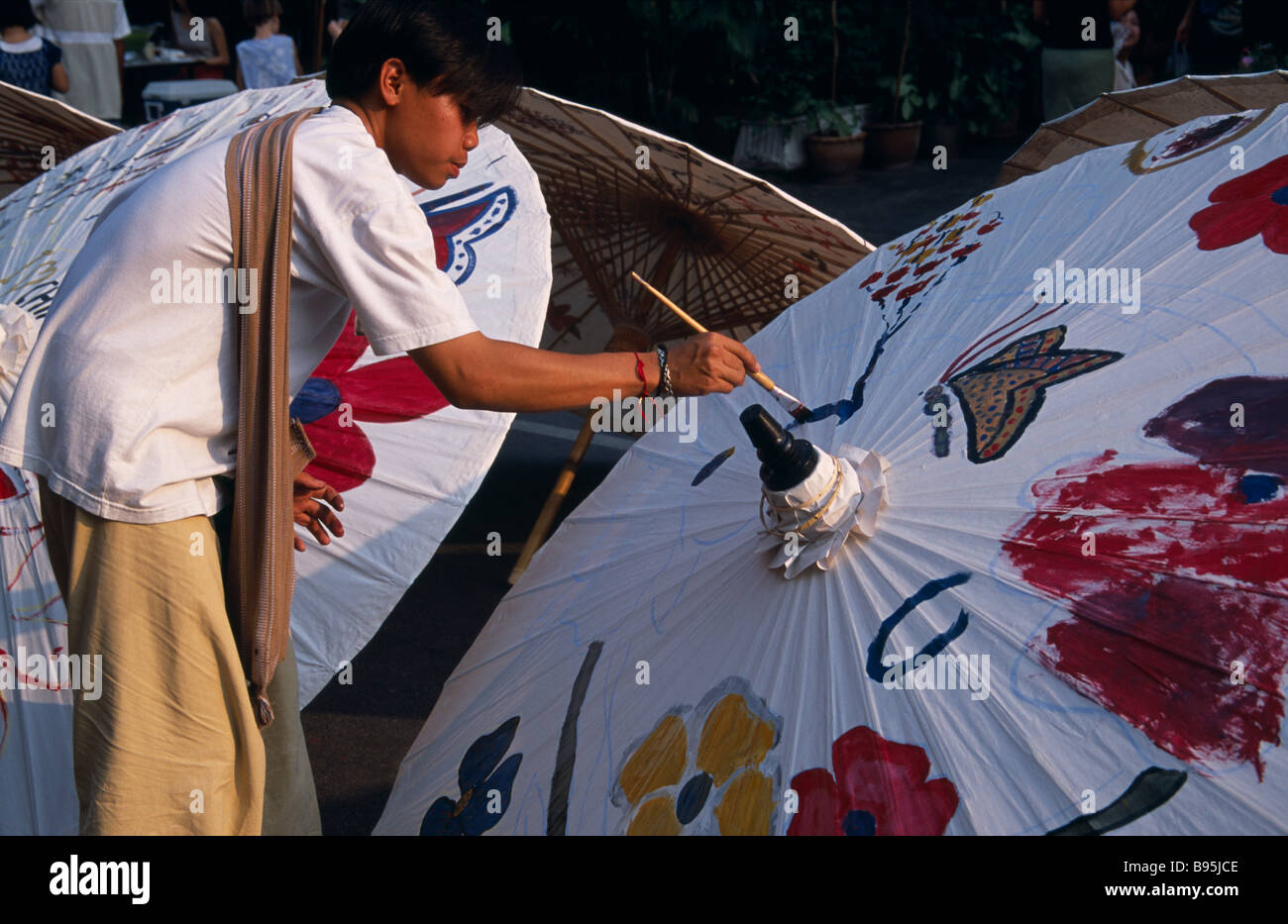 Thailandia Nord di Chiang Mai Tha Phae Road uomo locale di verniciatura tradizionale ombrellone in strada la concorrenza Foto Stock