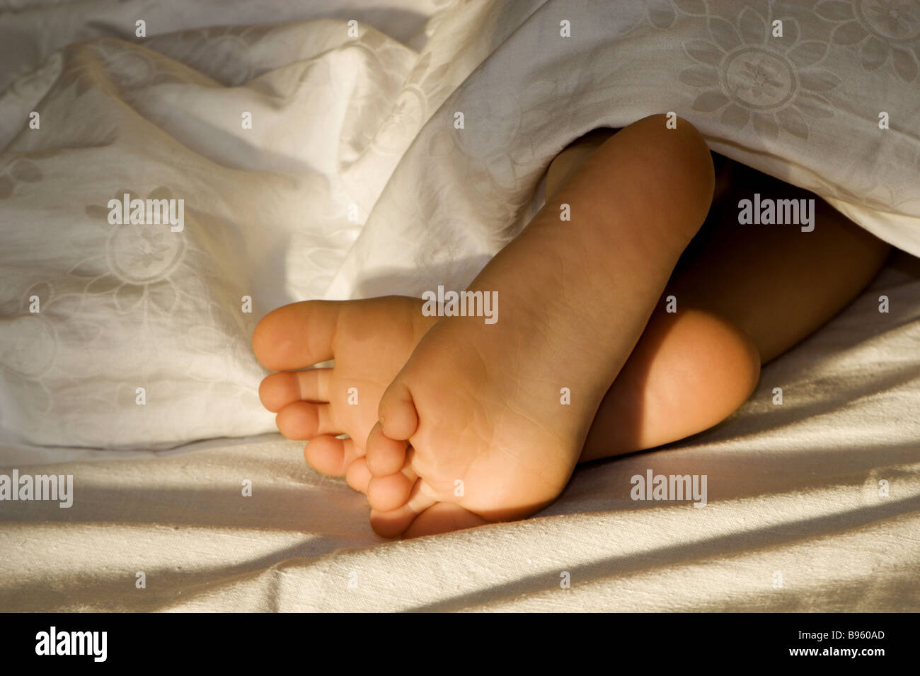 sveglia e piedi bambina sul letto Stock Photo