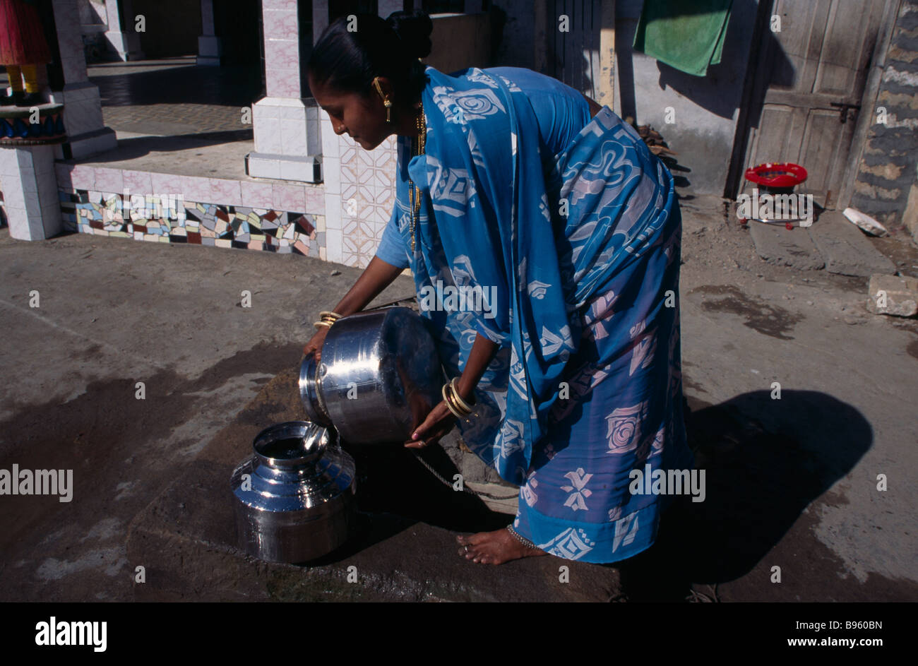 INDIA Gujurat Diu giovane donna indossa stampata blu sari il recupero di acqua dal bene in strada. Foto Stock