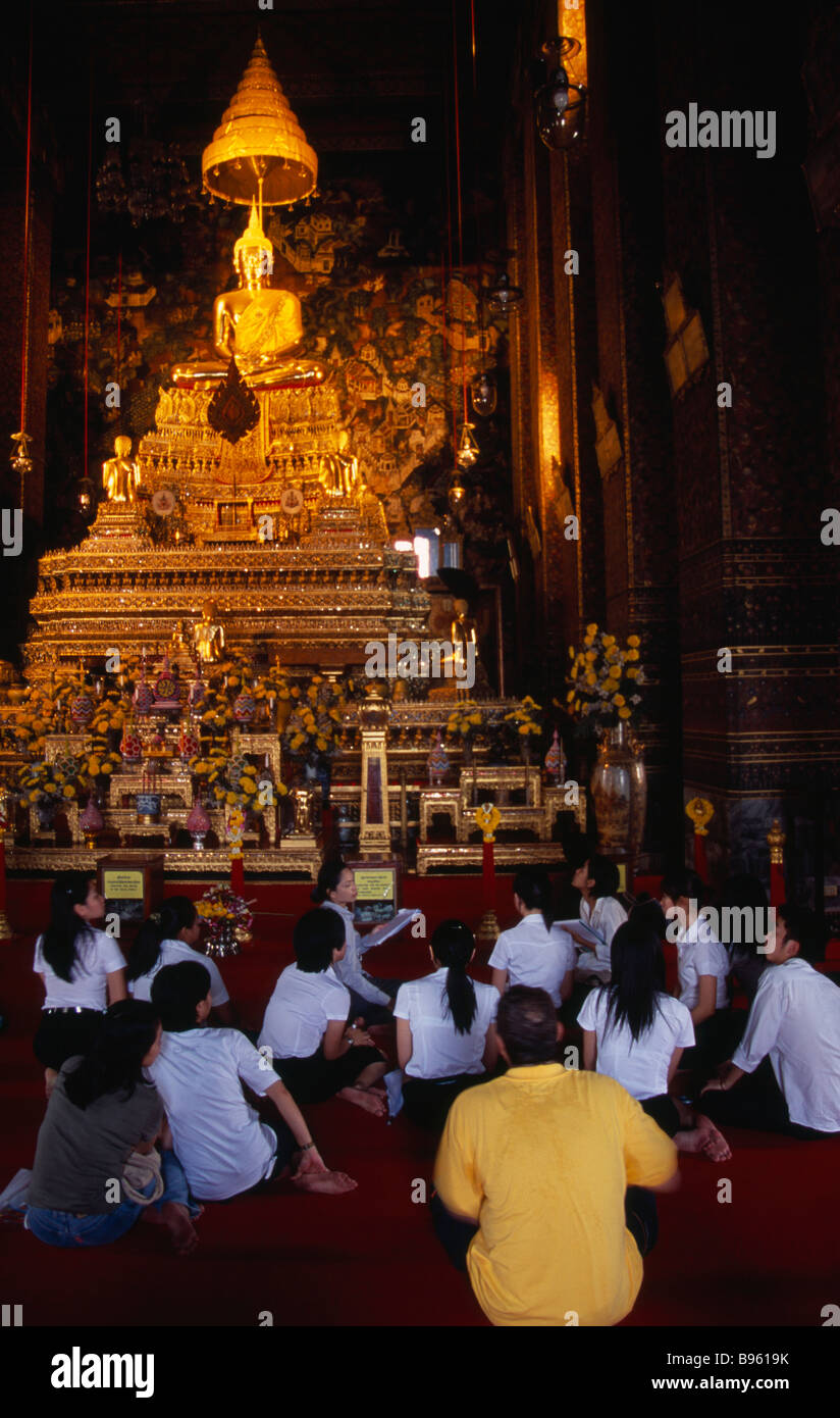 Il sud della Thailandia Bangkok Wat Pho tempio principale sala di preghiera con un gruppo di studenti di Thai e maestro insediato prima di Buddha d'Oro Foto Stock