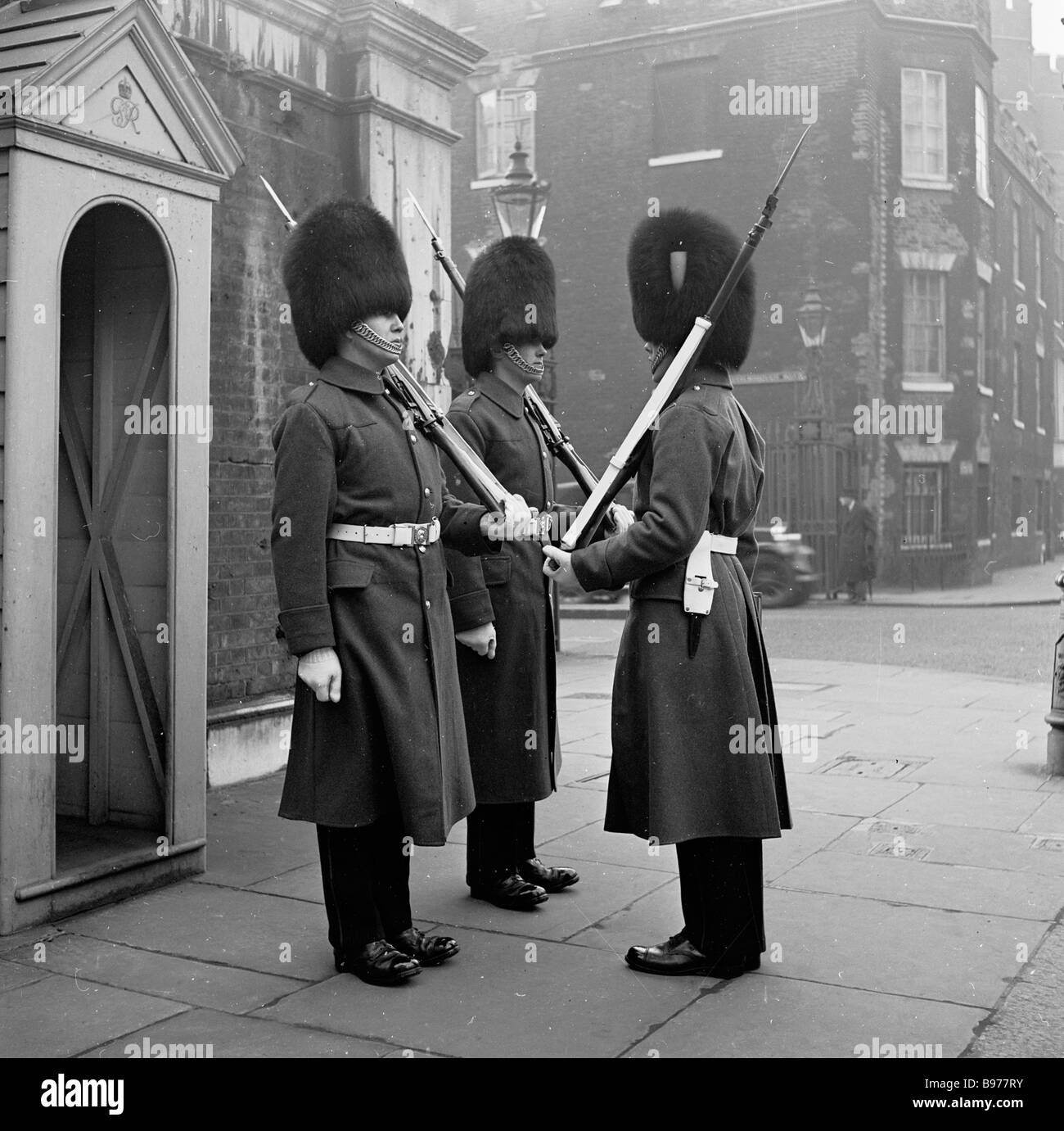 1950s, storico, tre guardie della regina che si levano in piedi all'attenzione sul marciapiede fuori di una capanna di sentry a Marlborough House, Londra, Inghilterra, Regno Unito. Foto Stock