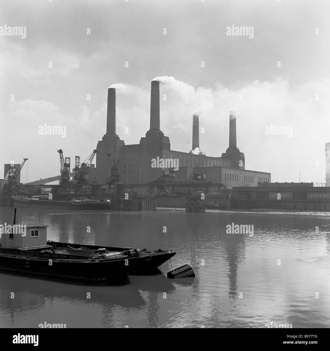 1950s, soffietti di fumo fuori dei quattro grandi camini in una centrale elettrica di Battersea funzionante, come visto dalla riva nord del Tamigi, Londra, Regno Unito. Foto Stock