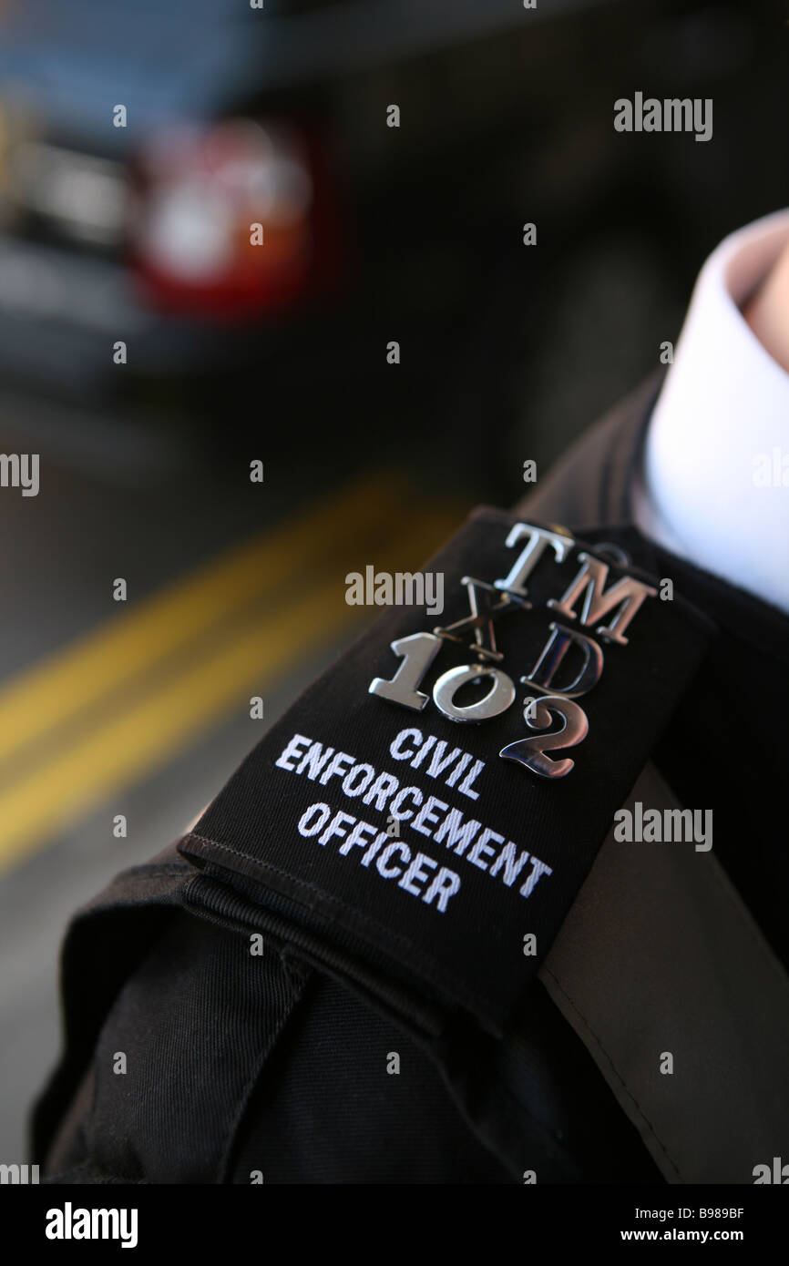 Il epaulette di un sistema civile di autorità di controllo che mostra il doppio di linee gialle restrictictions parcheggio in una strada del Regno Unito Foto Stock