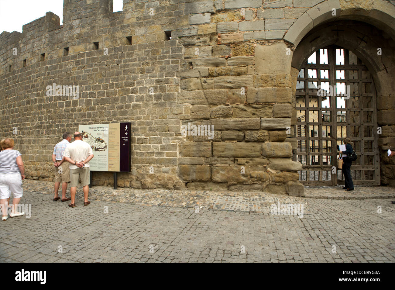I turisti esaminare una mappa turistica al di fuori delle mura del castello di Carcassonne Languedoc Francia Foto Stock
