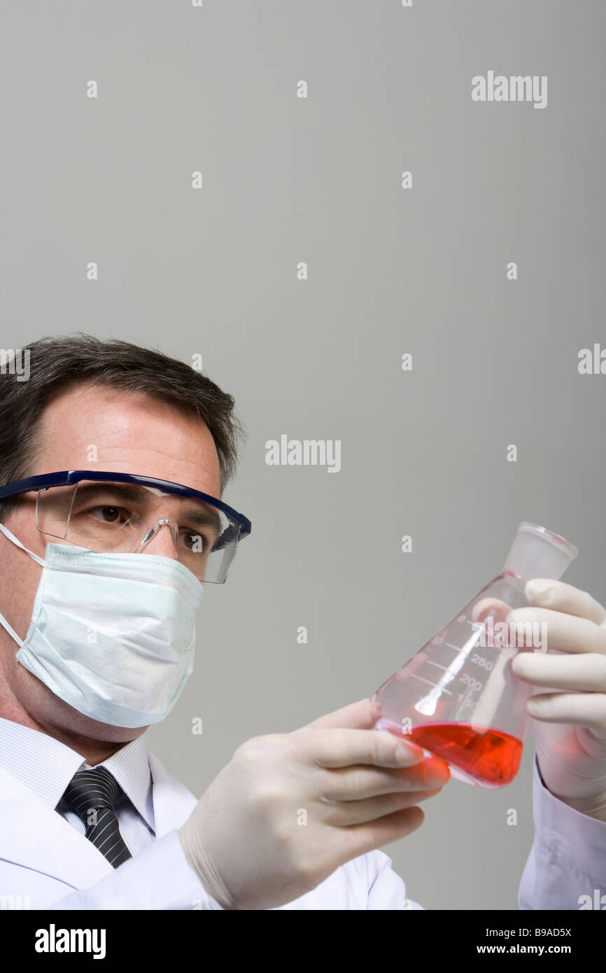Scienziato esaminando il liquido nel bicchiere Foto Stock