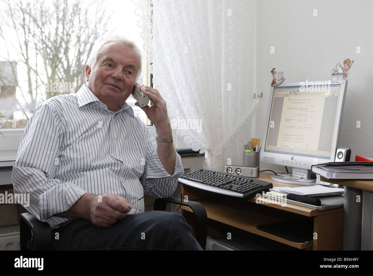 Titolare di pensione o di rendita utilizzando il telefono,seduti al computer Foto Stock