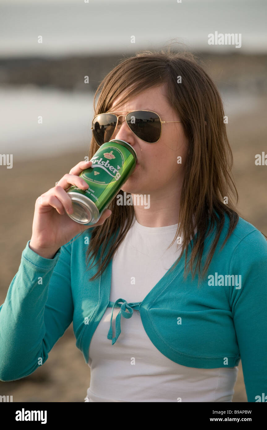 Una giovane ragazza donna studente di bere una lattina di Carlsberg lager birra booze esterno, REGNO UNITO Foto Stock