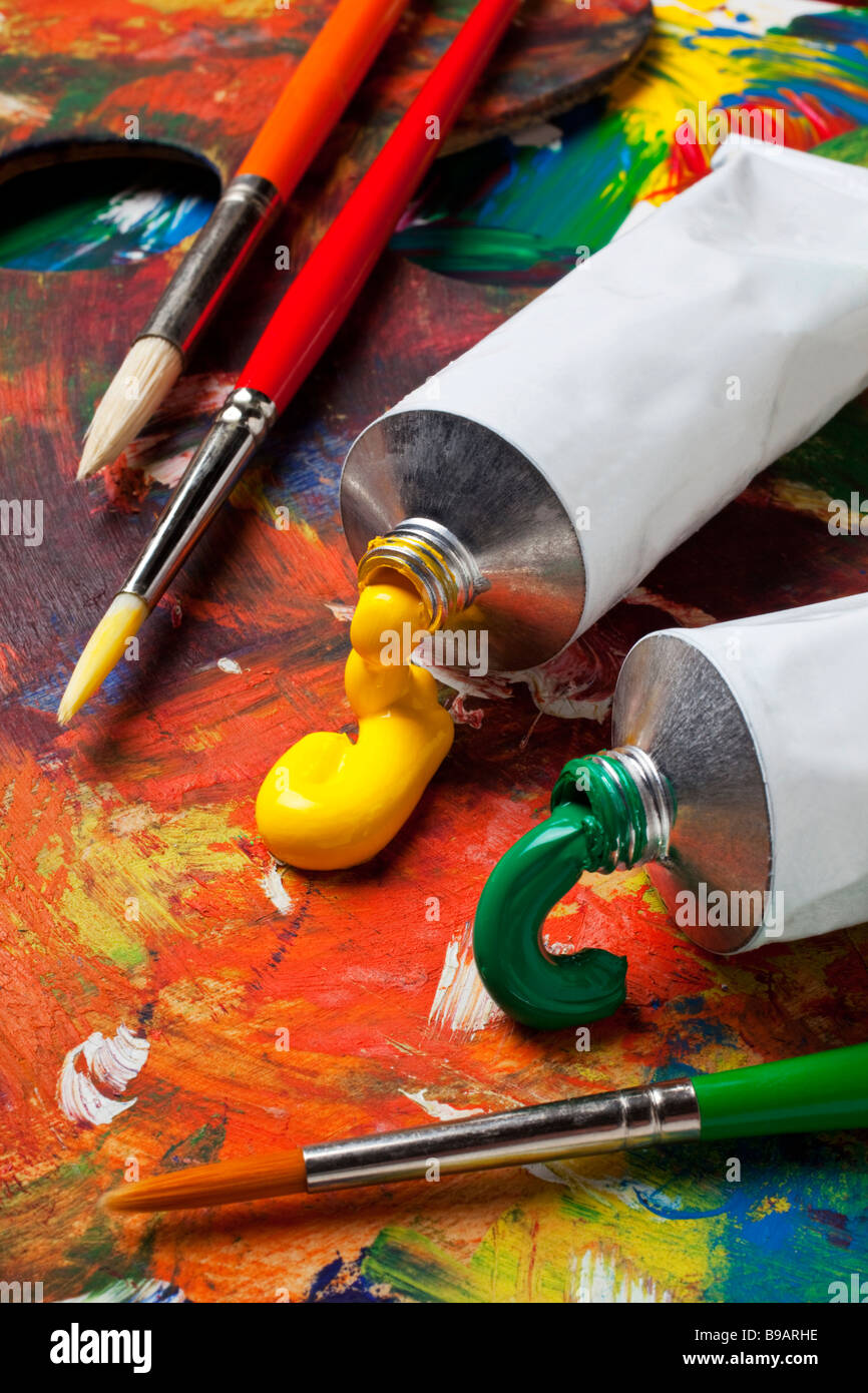 Tubi di vernice e pennelli su un artista pallet Foto Stock